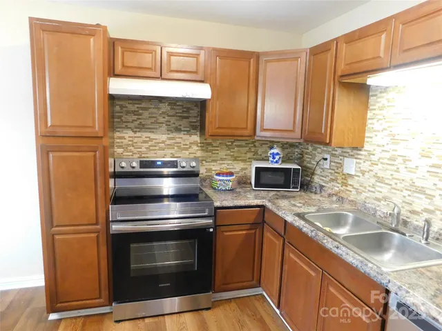 a kitchen with granite countertop a sink stove and refrigerator