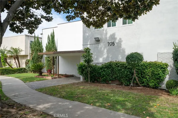 a view of a white house with a yard and table and chairs under an umbrella