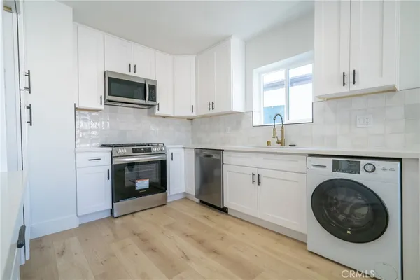 a kitchen with stainless steel appliances granite countertop grey cabinets a stove top oven a sink and dishwasher