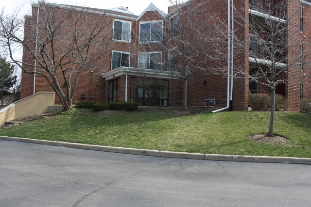 815 Leicester Road, Unit 115 Elk Grove Village, IL 60007 - Photo 1 of 1 a view of a brick building next to a yard