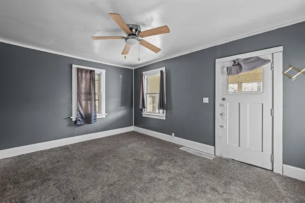 a view of an empty room with chandelier fan and window
