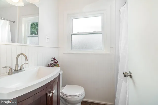 a bathroom with a toilet sink vanity and mirror