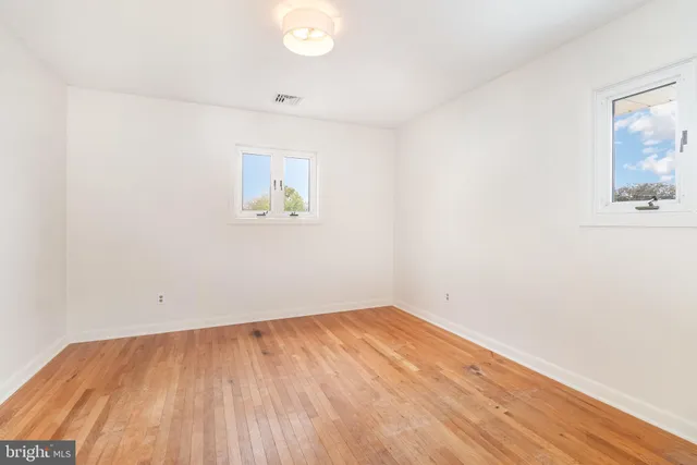 an empty room with wooden floor and window