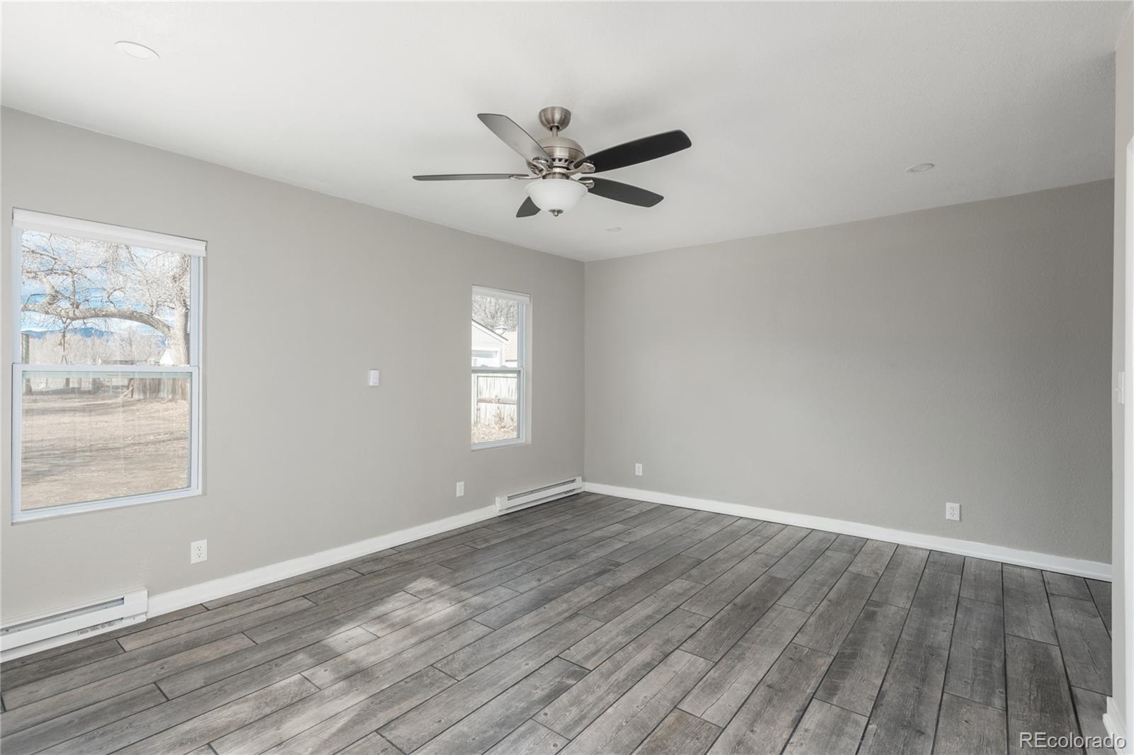4695 Parfet Street Wheat Ridge, CO 80033 - Photo 35 of 46 an empty room with wooden floor windows and fan
