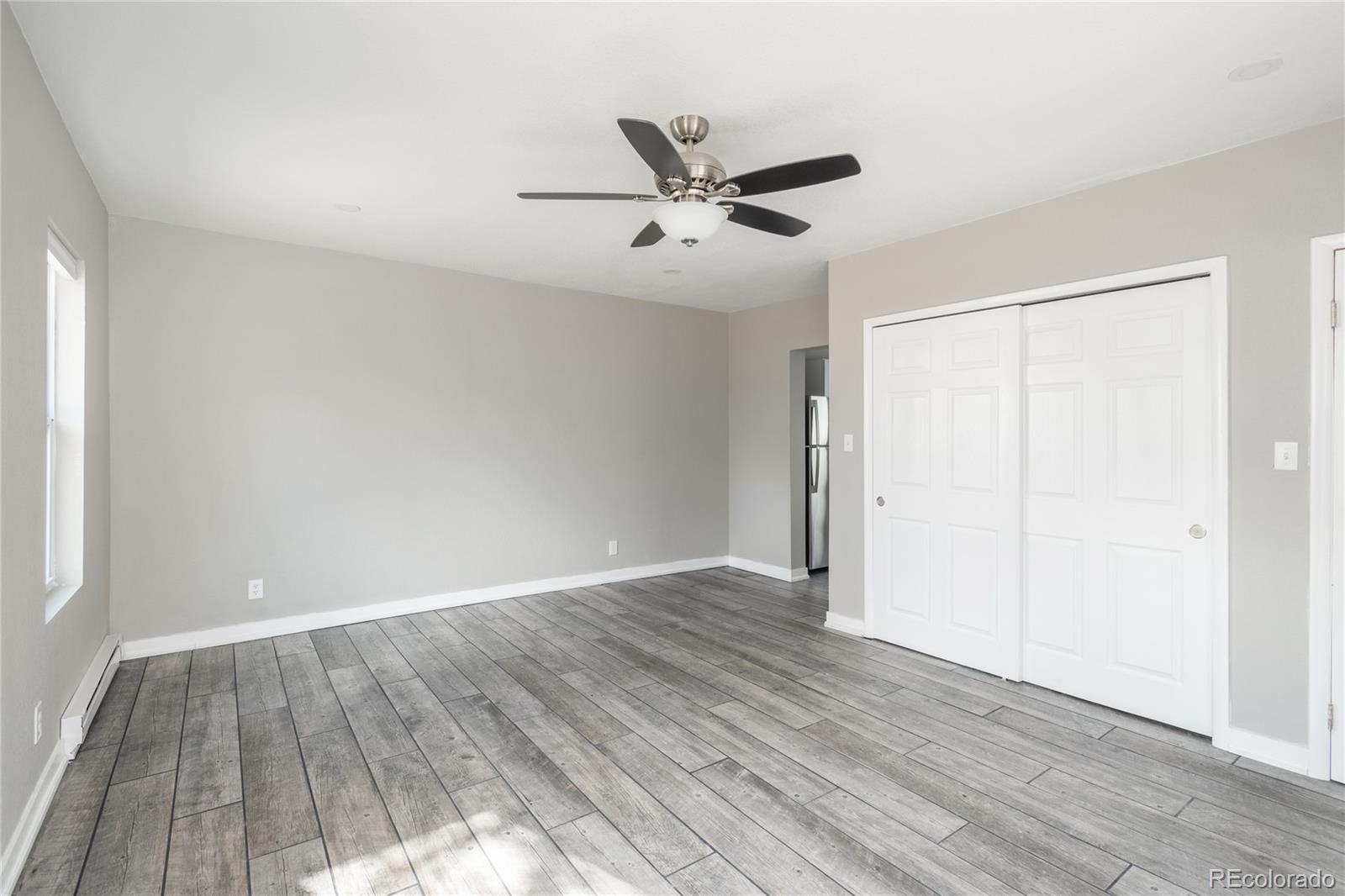 4695 Parfet Street Wheat Ridge, CO 80033 - Photo 36 of 46 an empty room with wooden floor a ceiling fan and windows