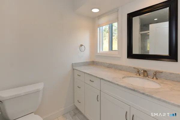 a bathroom with a granite countertop sink a toilet and mirror