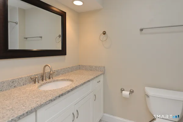 a bathroom with a granite countertop toilet sink and mirror