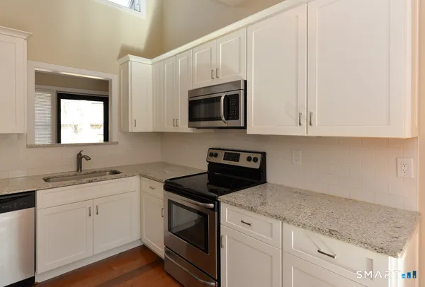 a kitchen with granite countertop white cabinets and white appliances