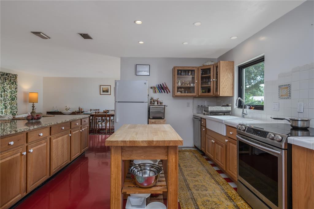 4790 Michael Lane Ponce Inlet, FL 32127 - Photo 11 of 28 a kitchen with stainless steel appliances granite countertop a stove top oven a sink dishwasher a dining table and chairs with wooden floor