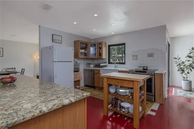 a kitchen with stainless steel appliances granite countertop a sink and a refrigerator