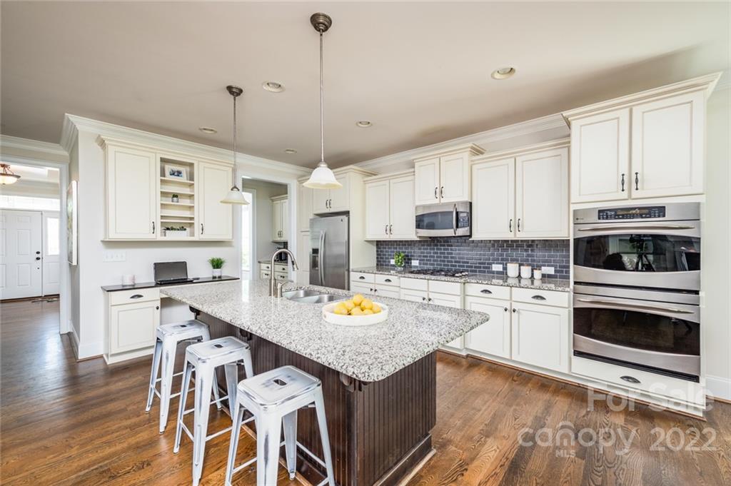 6009 Daphne Circle Fort Mill, SC 29708 - Photo 8 of 43 a kitchen with stainless steel appliances granite countertop a stove a sink dishwasher a microwave oven with a dining table and chairs with wooden floor