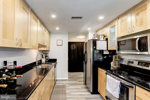 a kitchen with stainless steel appliances granite countertop a refrigerator a stove and a sink