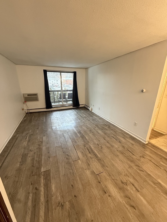 140 Kenrick Street, Unit 25 Boston, MA 02135 - Photo 2 of 12 an empty room with wooden floor and windows