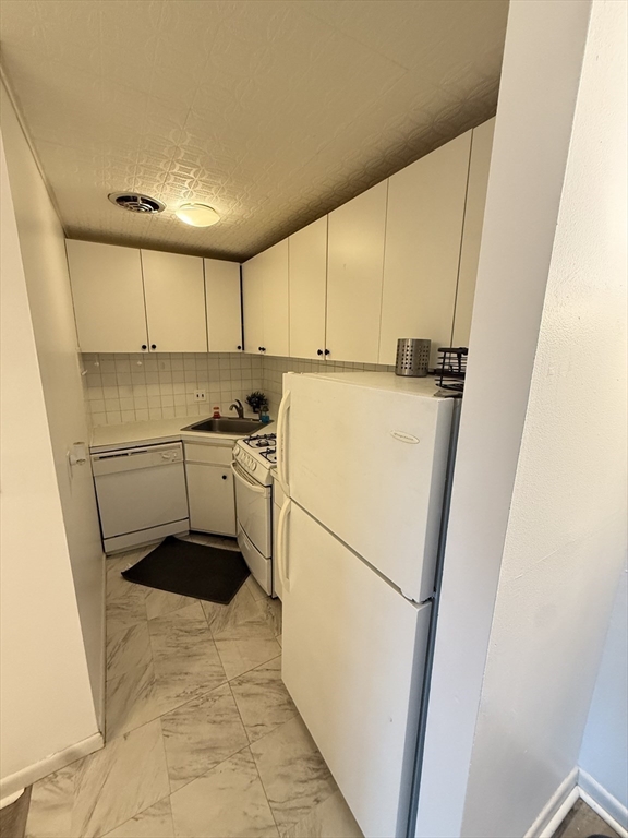140 Kenrick Street, Unit 25 Boston, MA 02135 - Photo 5 of 12 a white refrigerator freezer sitting in a kitchen