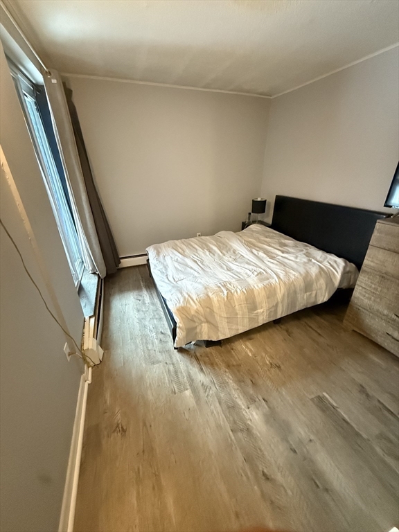 140 Kenrick Street, Unit 25 Boston, MA 02135 - Photo 8 of 12 a bedroom with a bed and wooden floor
