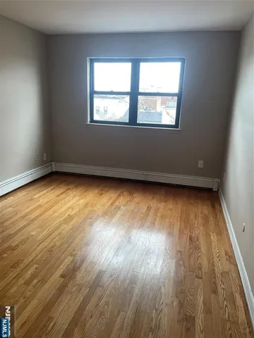a view of an empty room and wooden floor and a window