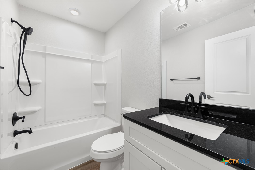 905 Martin Luther King Jr Lane, Unit A Temple, TX 76504 - Photo 16 of 23 a bathroom with a granite countertop sink a toilet and a bathtub