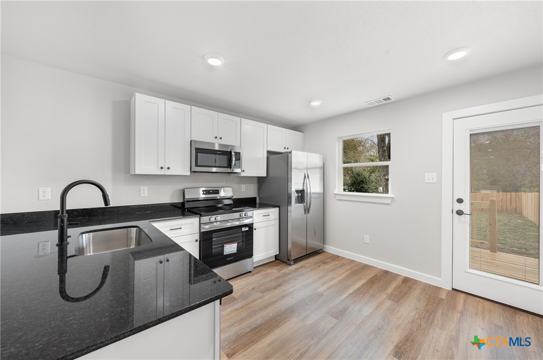 905 Martin Luther King Jr Lane, Unit A Temple, TX 76504 - Photo 8 of 23 a kitchen with granite countertop a stove a sink and a refrigerator
