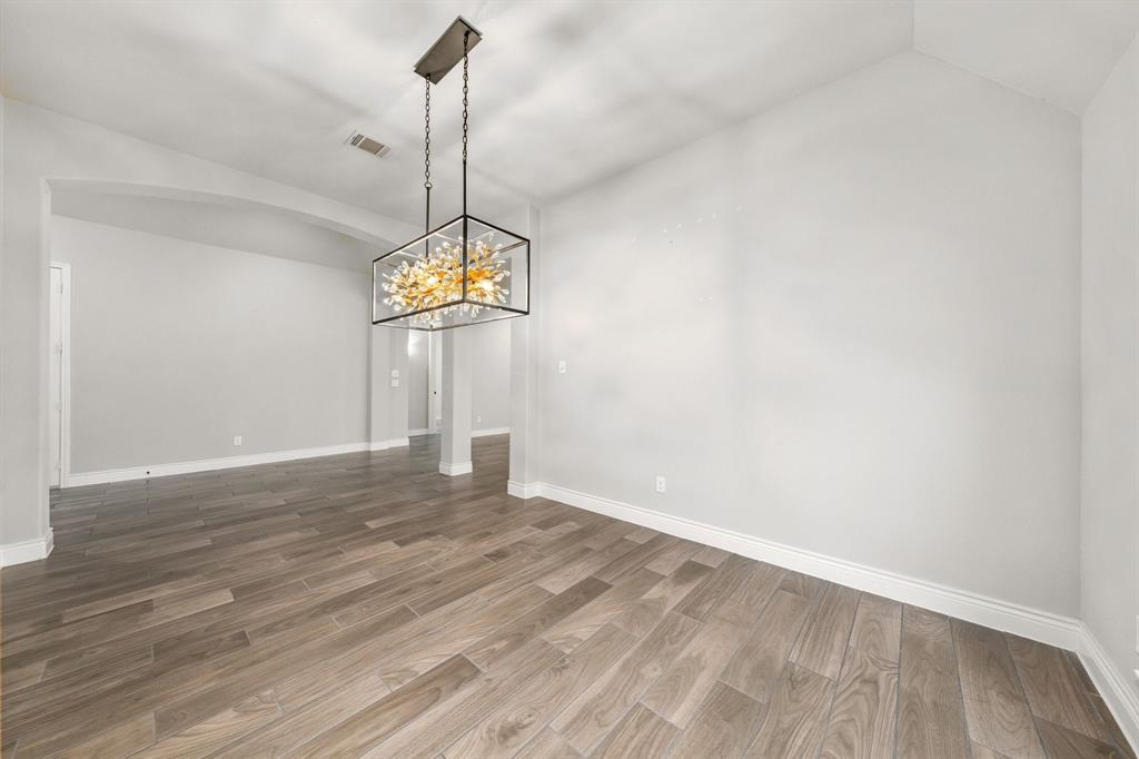 1501 Calcot Lane Forney, TX 75126 - Photo 7 of 34 Spacious room featuring wood-finish flooring, light grey walls, and an arched entry