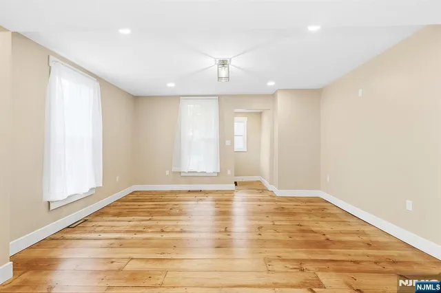 a view of an empty room with wooden floor and windows