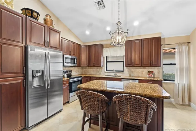 a kitchen with granite countertop a refrigerator a stove a sink cabinets and a dining table