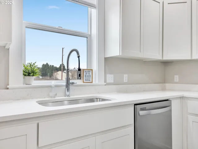 a kitchen with granite countertop white cabinets and a sink