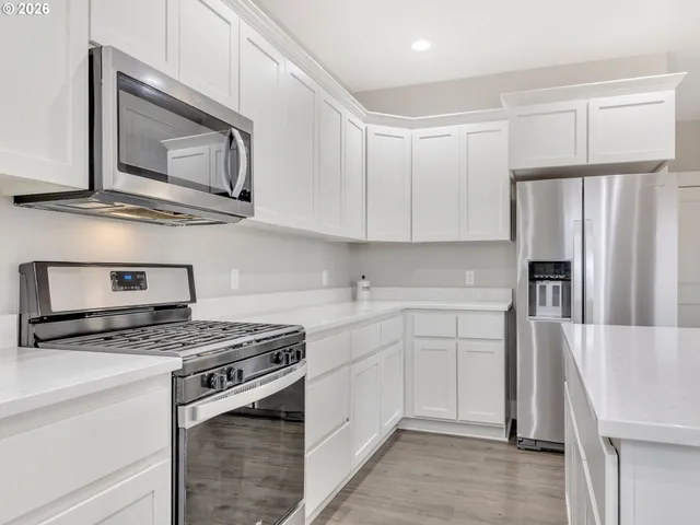 a kitchen with stainless steel appliances granite countertop a stove a microwave and a refrigerator