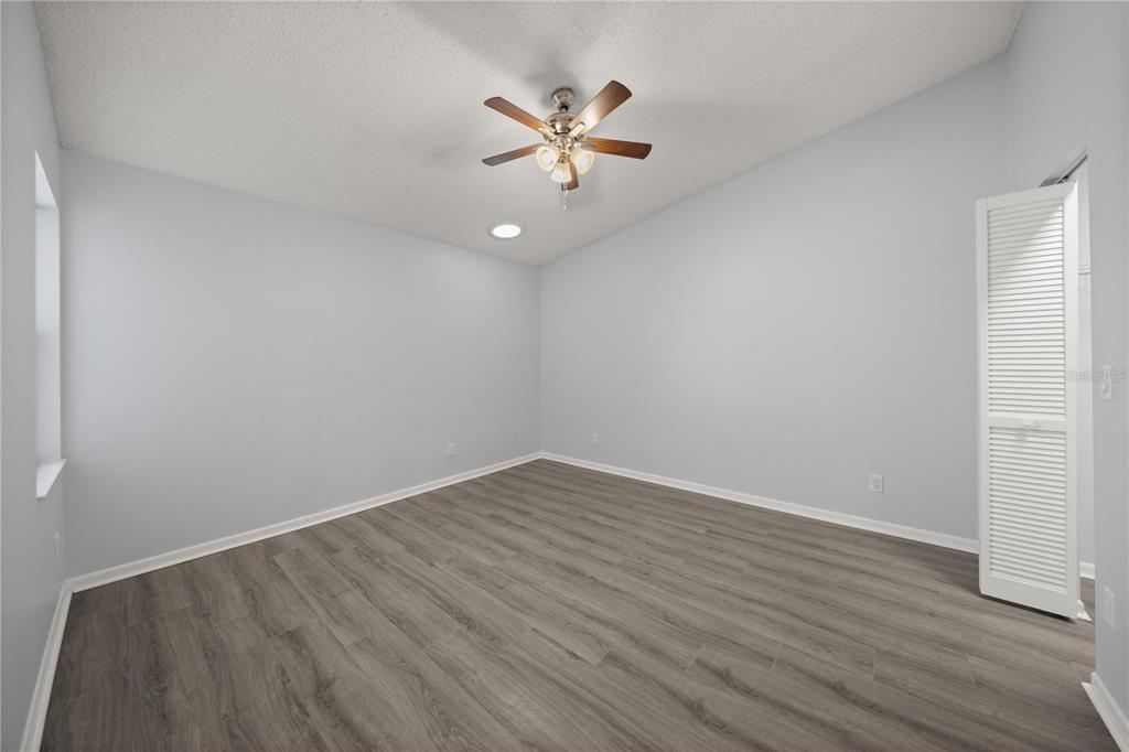 10441 Southwest 85th Court Ocala, FL 34481 - Photo 11 of 32 a view of an empty room with wooden floor and a ceiling fan