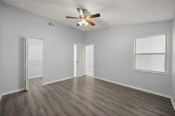 an empty room with wooden floor and windows