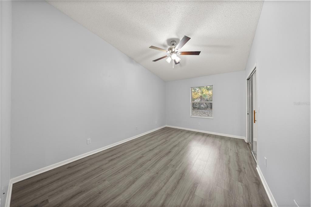 10441 Southwest 85th Court Ocala, FL 34481 - Photo 22 of 32 an empty room with wooden floor chandelier fan and windows