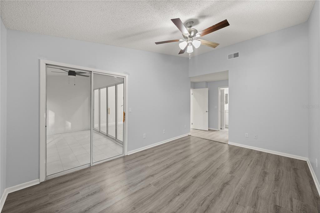 10441 Southwest 85th Court Ocala, FL 34481 - Photo 23 of 32 a view of an empty room with wooden floor and a ceiling fan