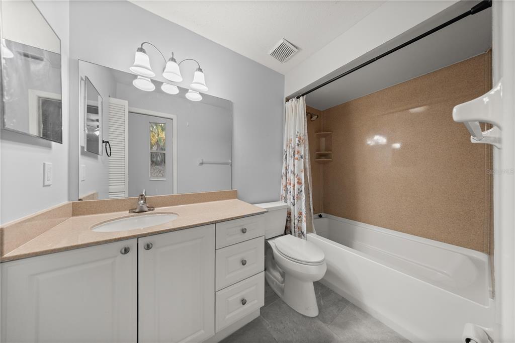 10441 Southwest 85th Court Ocala, FL 34481 - Photo 25 of 32 a bathroom with a granite countertop sink a toilet and bathtub