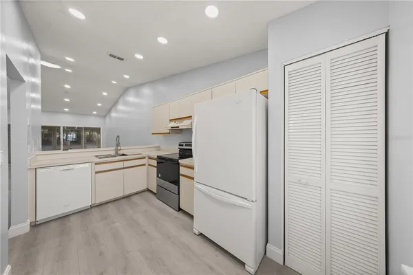 a kitchen with a refrigerator and white cabinets