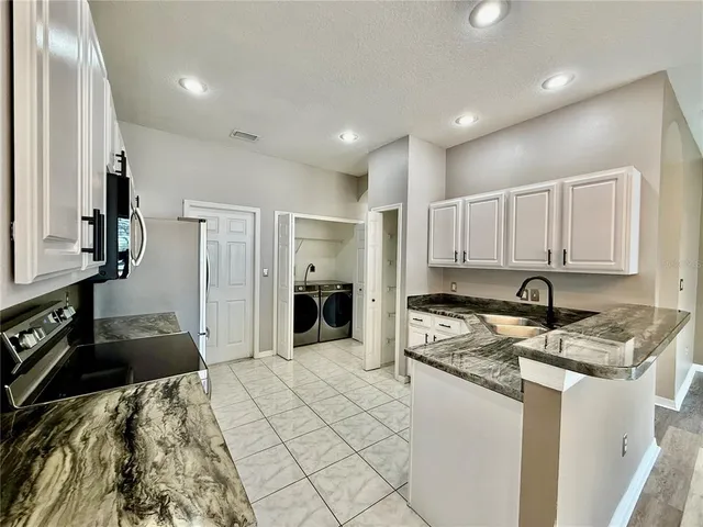 a kitchen with stainless steel appliances granite countertop a sink a stove and cabinets