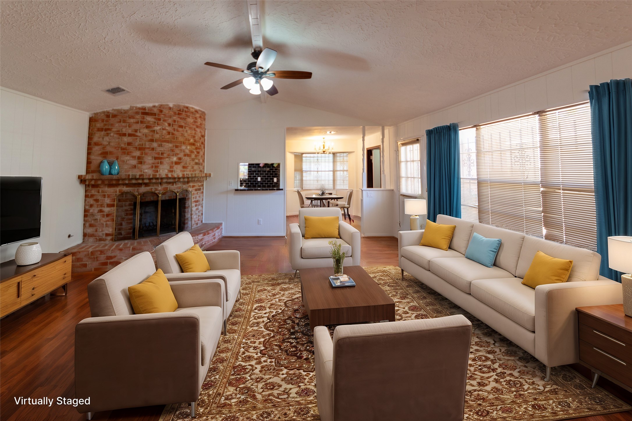 8826 Roos Road Houston, TX 77036 - Photo 6 of 42 A cozy living room with a warm, brick fireplace and ample natural light from large windows. The space is virtually staged with modern furniture, including sofas and a coffee table, and features hardwood floors and a ceiling fan.