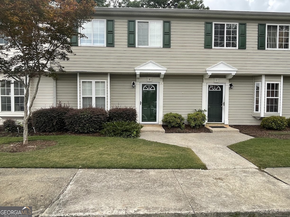 a front view of a house with a yard and potted plants