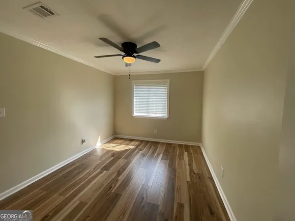 an empty room with wooden floor ceiling fan and windows