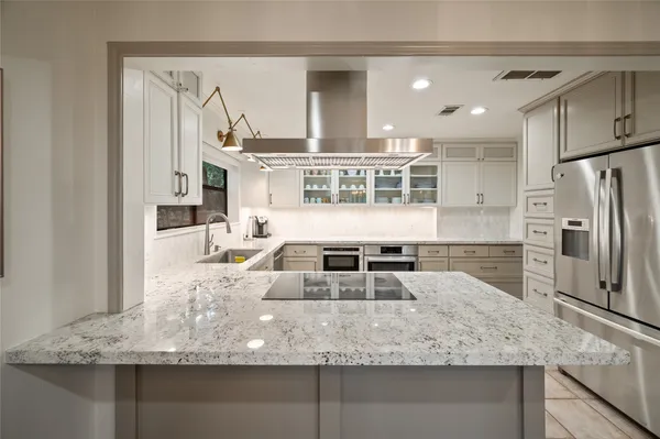 a kitchen with kitchen island granite countertop a sink and refrigerator