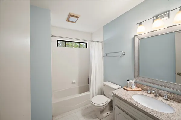 a bathroom with a granite countertop sink toilet a mirror and shower