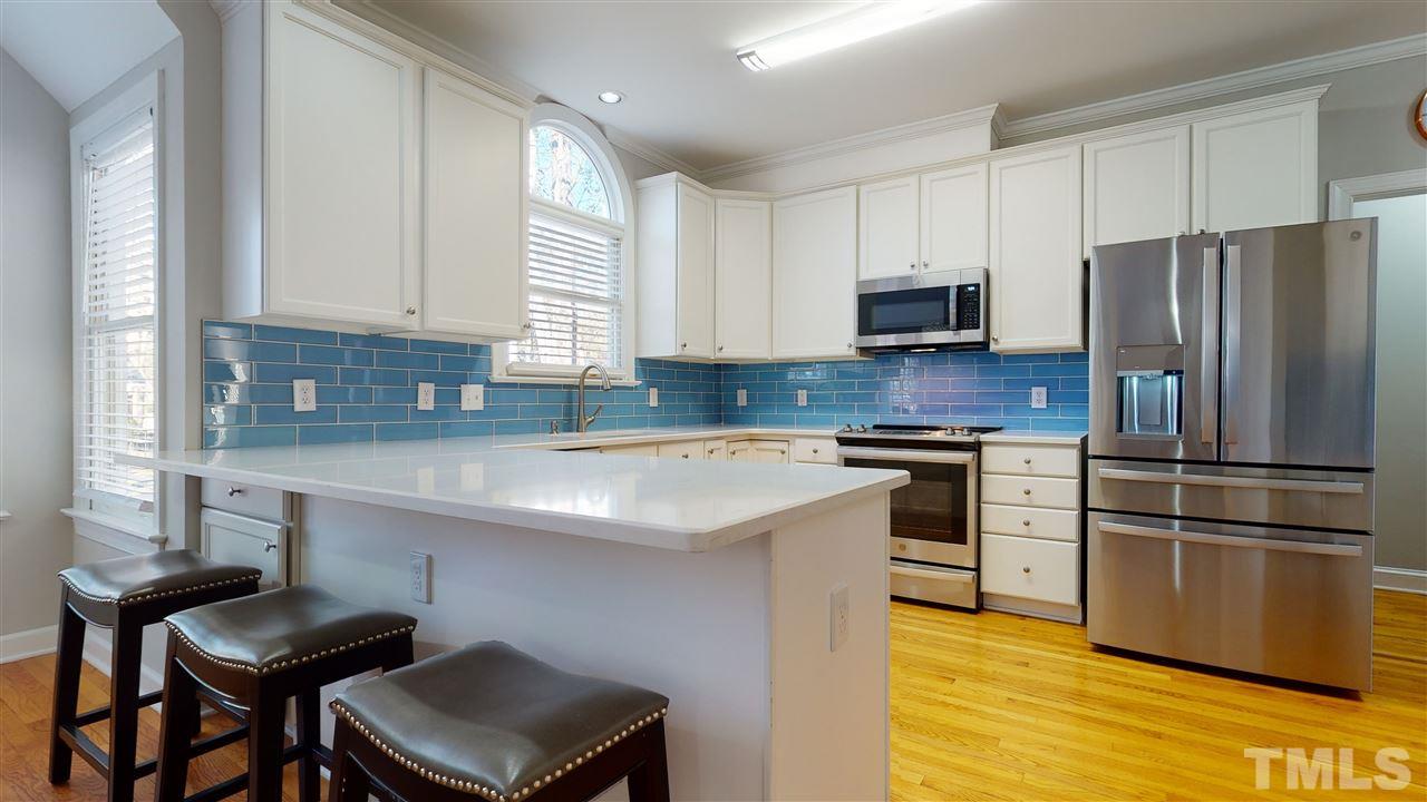 4708 Alistar Court Raleigh, NC 27612 - Photo 13 of 30 a kitchen with a refrigerator and a stove top oven