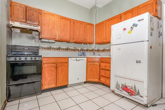 a kitchen with granite countertop a white stove top oven and cabinets
