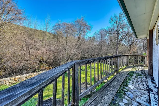 a balcony with wooden floor and trees in the back