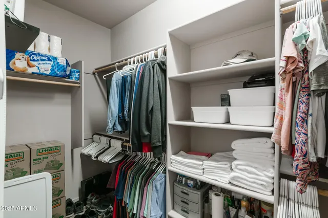 a view of walk in closet with clothes and shoes