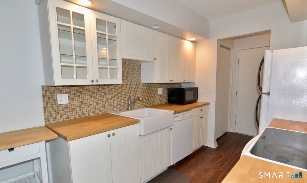 125 Warner Hill Road, Unit 67 Stratford, CT 06614 - Photo 4 of 14 Designed with both style and comfort in mind, the kitchen features butcher-block countertops, a farmhouse sink, white appliances, and a classic tiled backsplash, opening effortlessly into the dining area.