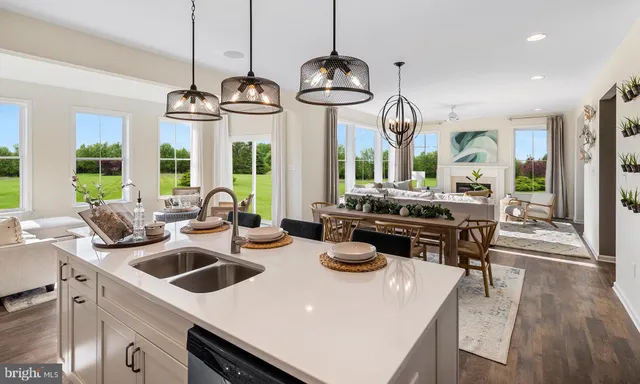 a kitchen with sink a stove and chairs with wooden floor