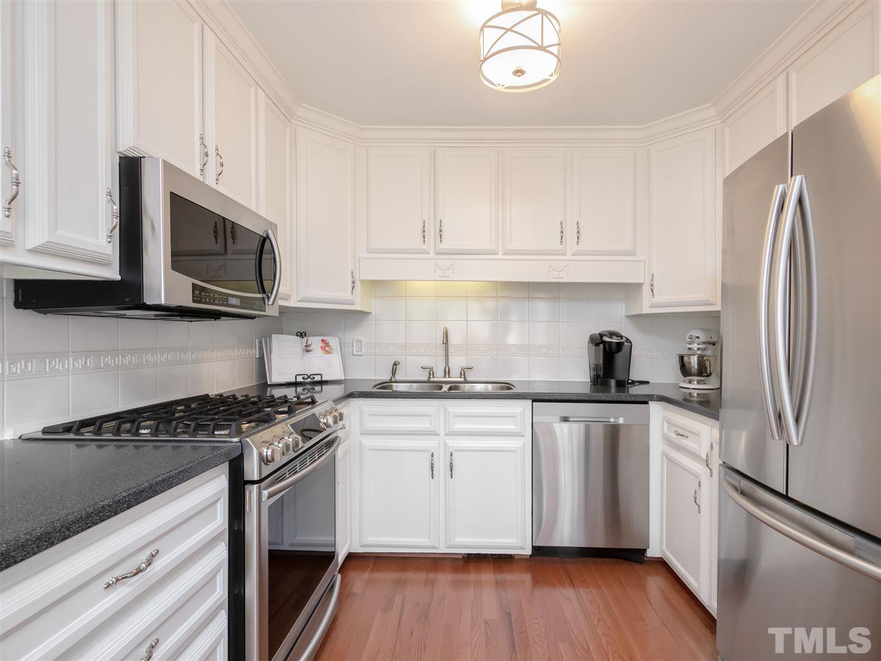 3745 Lassiter Mill Road Raleigh, NC 27609 - Photo 8 of 25 a kitchen with stainless steel appliances granite countertop a stove top oven a sink dishwasher and a refrigerator with wooden floor