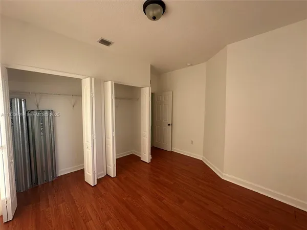 an empty room with wooden floor and closet