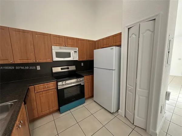 a kitchen with granite countertop a refrigerator and a stove top oven