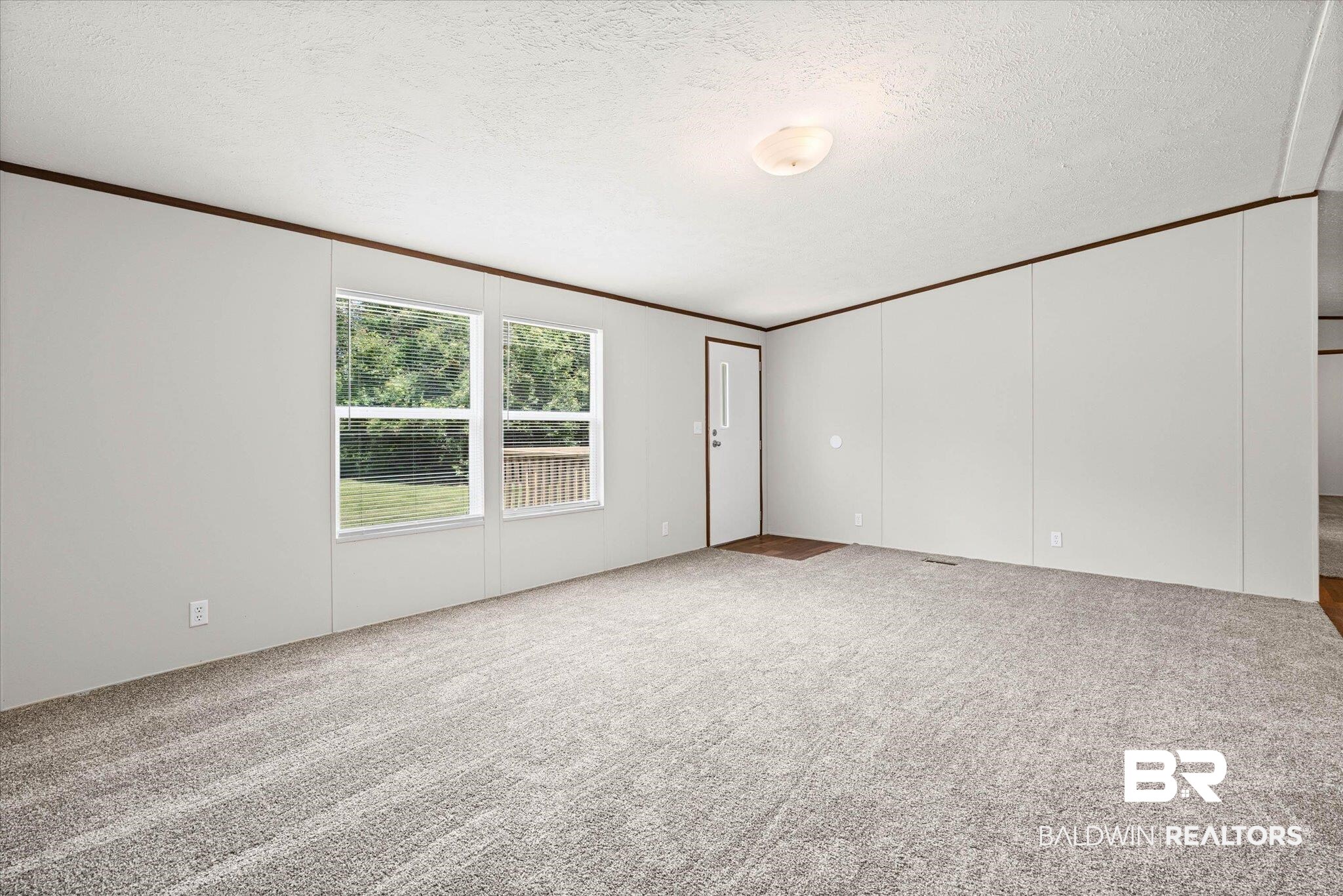 25366 Pollard Road Daphne, AL 36526 - Photo 4 of 22 Spacious interior room with light gray wall panels and contrasting dark wood trim