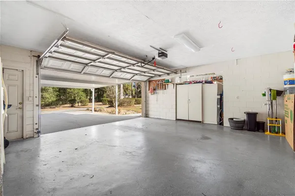 a view of white house next to a yard with large trees